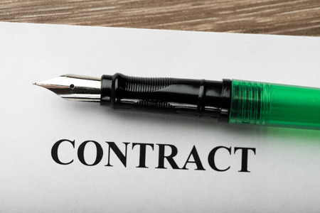 Pen and contract papers on wooden deskの写真素材