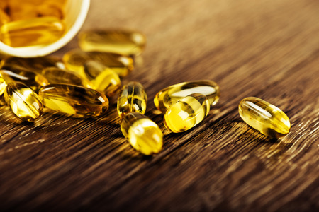 Pills spilling out of a jar on a wooden surfaceの写真素材