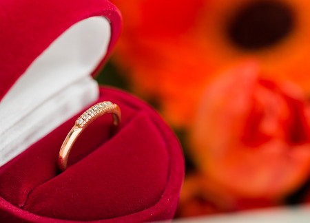 diamond ring in a velvet red box, flower backgroung