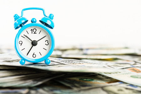 Time is money. Alarm clock and dollar banknotes.