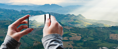 Tourist taking a picture of Sun rays shining down on hills in San Marinoの写真素材