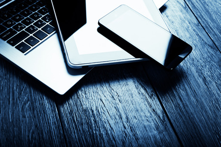 keyboard with phone and tablet pc on wooden desk.  Blue tonedの写真素材