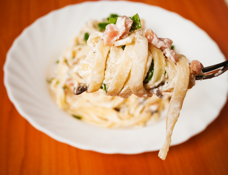 Spaghetti . Fettuccine carbonara in a white bowl, garnished with bacon, mushrooms and parsley. Delicious creamy sauce.の写真素材