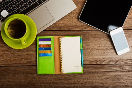 Office desk with laptop computer, tablet pc, planner, pen, mobile smartphone and cup of tea.の写真素材