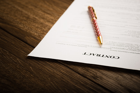 Pen and contract papers on wooden deskの写真素材