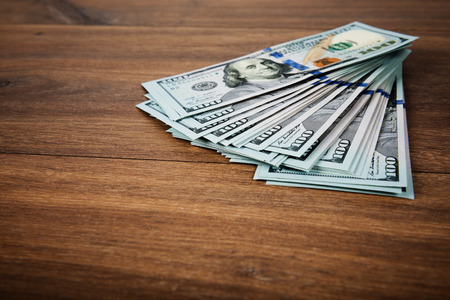 new 100 US dollars 2013 edition banknotes (bills) on wooden background