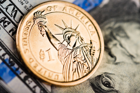 one us dollar coin on american banknotes
