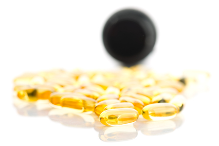 shiny yellow oil capsule spilling out of pill bottleの写真素材