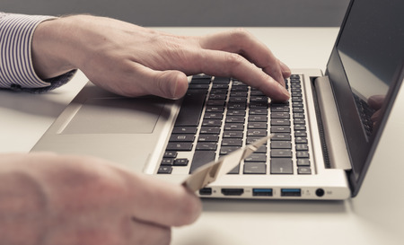 Businessman hand holding credit card and use laptopの写真素材