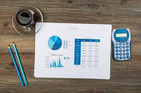 Office workplace table with report pages, coffee cup and calculatorの写真素材
