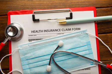 Health insurance claim form with stethoscope and surgical maskの写真素材