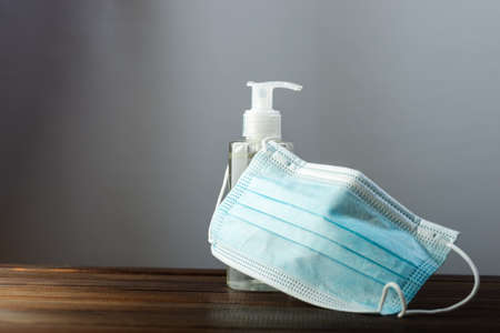 Medical face mask with alcohol sanitizer gel hand wash on wood table for covid-19の写真素材