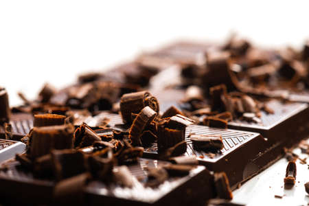 Curls and pieces of tasty chocolate on white tableの写真素材