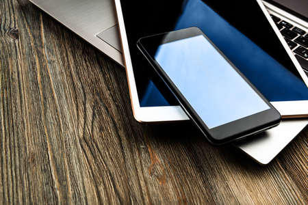 laptop with phone and tablet pc on wooden deskの写真素材