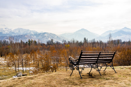 Empty bench in the park and mountains in the background. Almaty. Kazakhstan