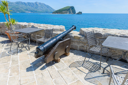 An old cannon among the tables in a cafe. Ancient citadel in Budva. Montenegroの写真素材