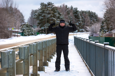 A cheerful man in black winter clothes is holding two fingers up and welcomes you to Russiaの写真素材