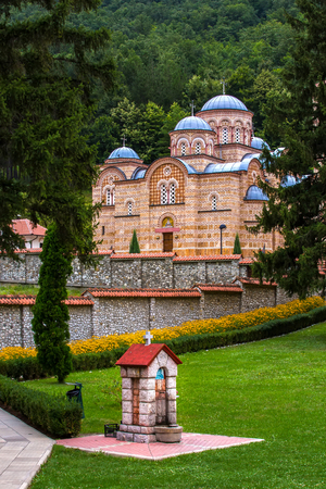 Orthodox church with a beautiful stone fence surrounded by nature, in the foreground a water tap....