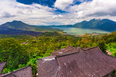 Panoramic view of a lake surrounded by clouds in the sky. Roof in the foreground. Danau Batur, Gunung Batur, Kintamani, Bali, Indonesia.の写真素材