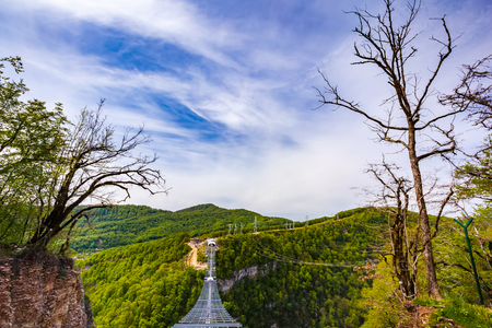 Skypark AJ Hackett Sochi, Adler, Russia - May, 2016. A metal pedestrian suspension bridge across the Mzymta River canyon in clear sunny weather against the backdrop of a colorful green forest.のeditorial素材