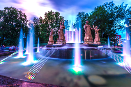 Sculptures of beautiful girls in national dresses in a multi-colored highlight against the background of the night evening sky.のeditorial素材