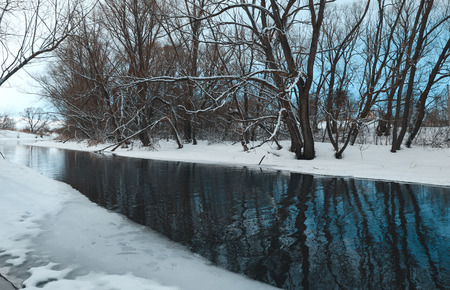 Springtime.Cloudy landscape with trees growing on the bank of the river.Melting snow and ice.White clouds in spring blue sky.の写真素材