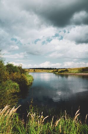 Beautiful view of river and dark stormy clouds over the landの写真素材
