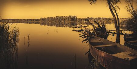 Tranquil summer morning scene with boats on river bank.の写真素材