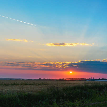Summer sunset rural landscape with dramatic sky over the fields.