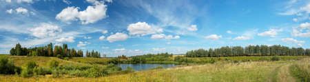 Bright summer panoramic landscape with beautiful lake and green hillsの写真素材
