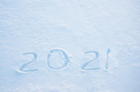 Handwritten digits 2021 in a fresh crisp snow illuminated by the light of rising sun.New year concept.の写真素材