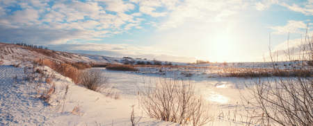 Sunny panoramic early springtime landscape.Beautiful view of frozen river and snow covered fields...