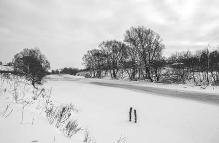 Black and white rural winter or springtime landscape with frozen riverの写真素材