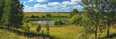 Beautiful summer rural landscape with lake and farm fields in sunny day.Good summertime panoramic view.の写真素材