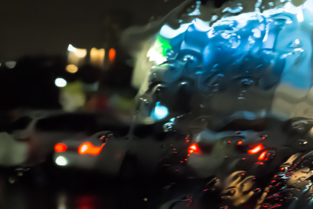 illuminated buildings of the night city through the streams of rain through the car glassの写真素材