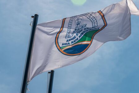 The flag of Agia Napa municipality. Flag on the flagpole and the stereet lamp post. The wind inflates the flag.の写真素材
