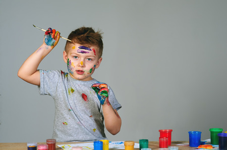 Boy with hands painted in colorful paintsの写真素材