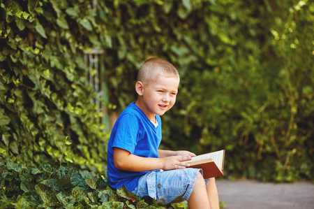 boy sitting with a book in the yardの写真素材