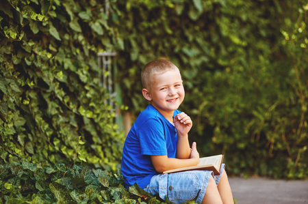 boy sitting with a book in the yardの写真素材