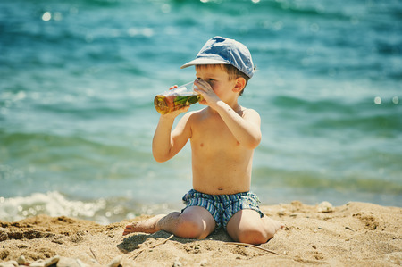 little boy at the beach with a glass of home-made refreshing drink.の写真素材