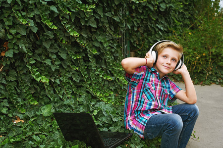 Boy listening to music in the city with a laptopの写真素材