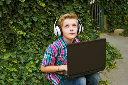 Boy listening to music in the city with a laptop