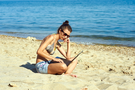 a young emotional girl with laptop at the seaの写真素材