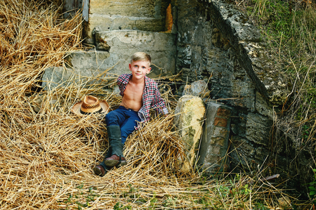 The boy in riding clothes posing near the barnの写真素材