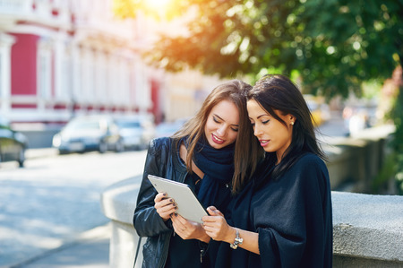 two beautiful young girls, look at the photos on your tablet, socializing on the Internetの写真素材