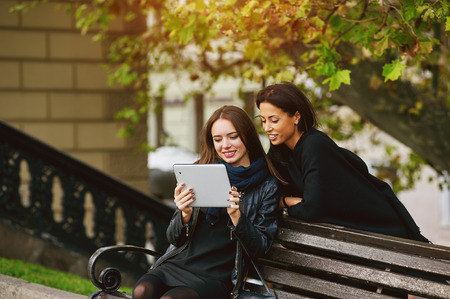 two beautiful young girls, look at the photos on your tablet, socializing on the Internetの写真素材