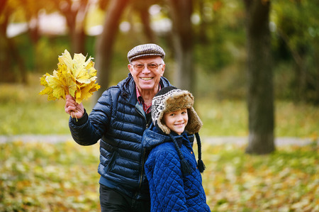 Grandfather walking with grandson playing in autumn Parkの写真素材