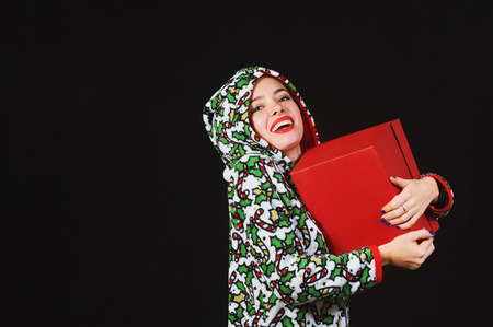 A truly sweet girl with a gift. Woman holding a red box on a dark background, dressed in a...