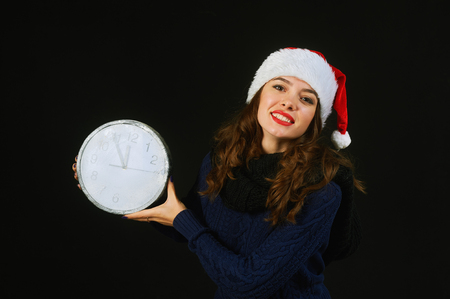 Young woman in Santa hat holding clock. Christmas timeの写真素材