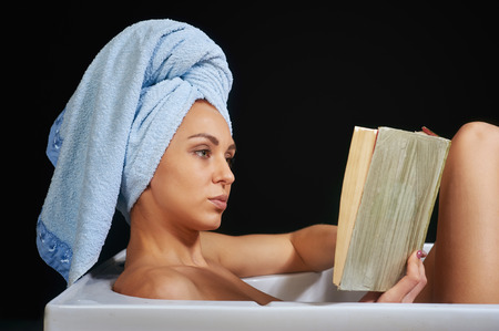 girl reading a book while taking bathの写真素材